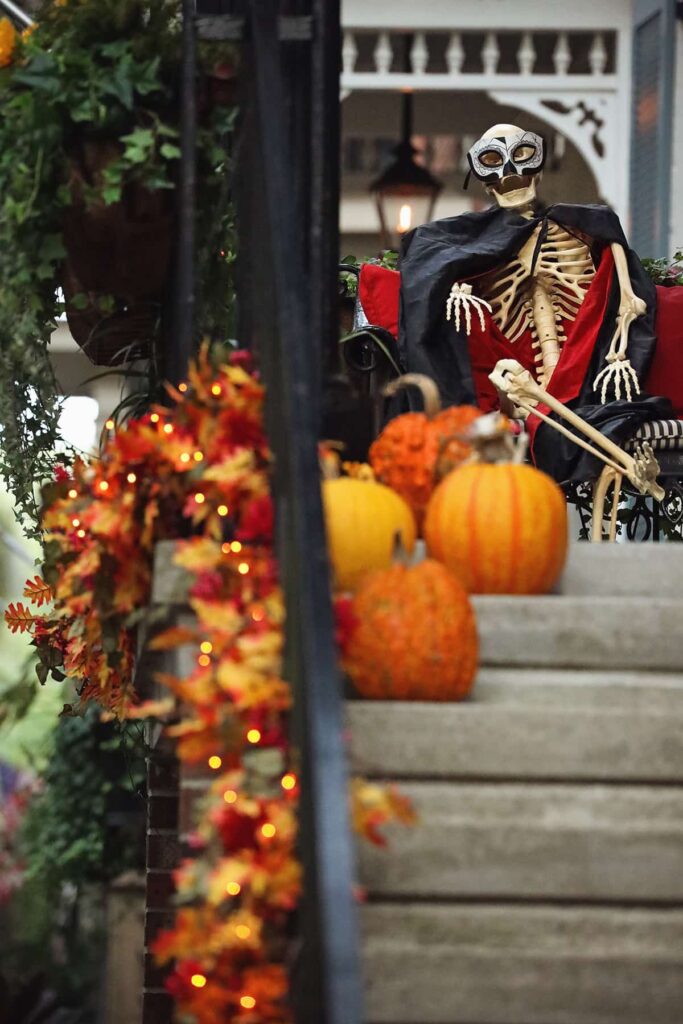 The staircase to an elegant home on Jones Street in Savannah, Georgia, is decorated for Halloween with orange and red garlands, pumpkins, and a skeleton dressed in a Phantom of the Opera costume