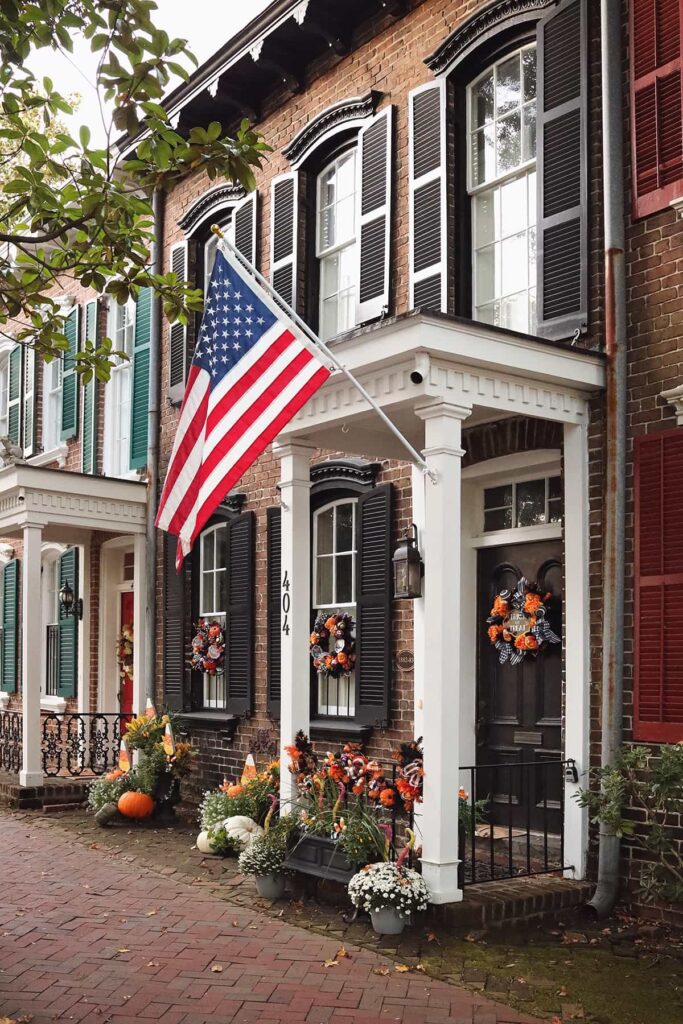 Row homes decorated for Halloween in Savannah with fall wreaths on the windows colorful potted plants with fall accents in front of the doors