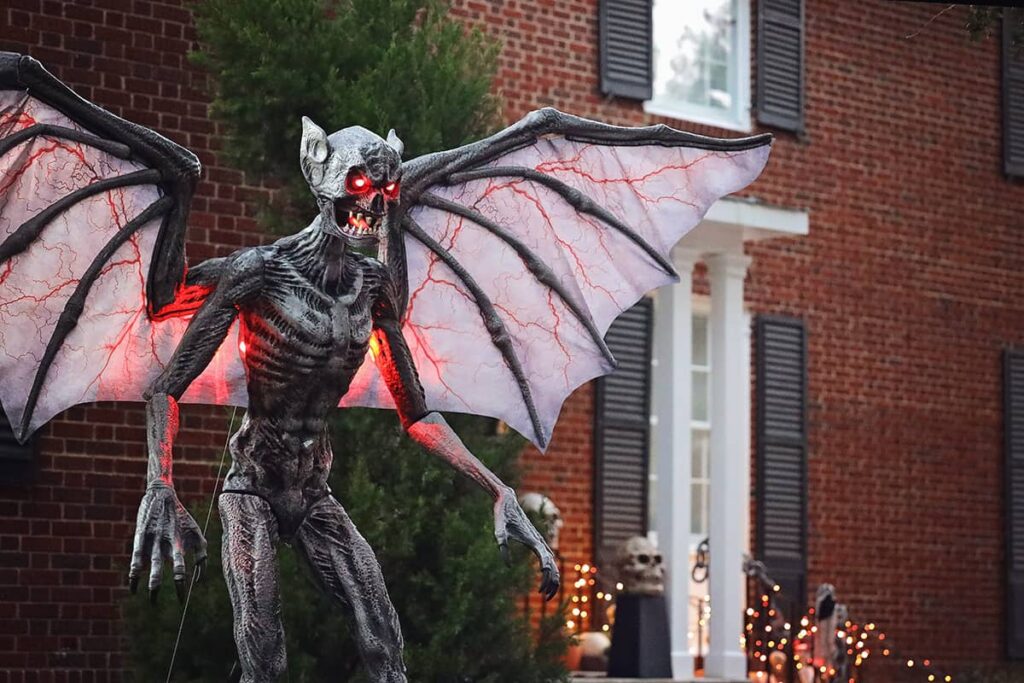 A winged demon with glowing red eyes decorates the yard of a stately brick home in Ardsley Park for Halloween in Savannah