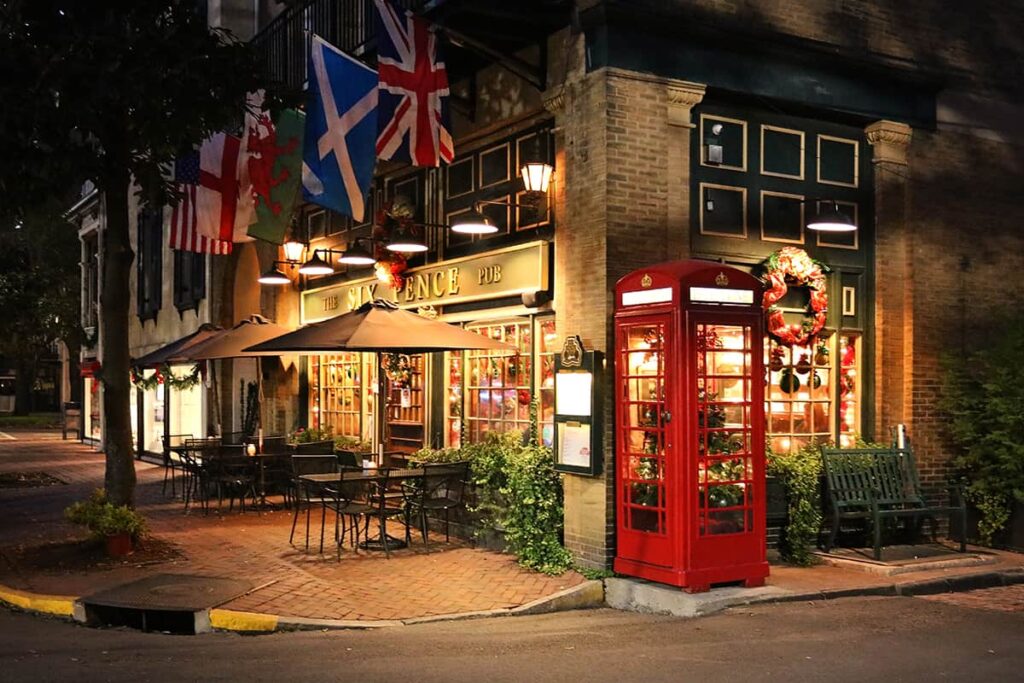 Six Pence Pub is illuminated by holiday lights, and a Christmas tree is visible inside their iconic red British-style telephone booth