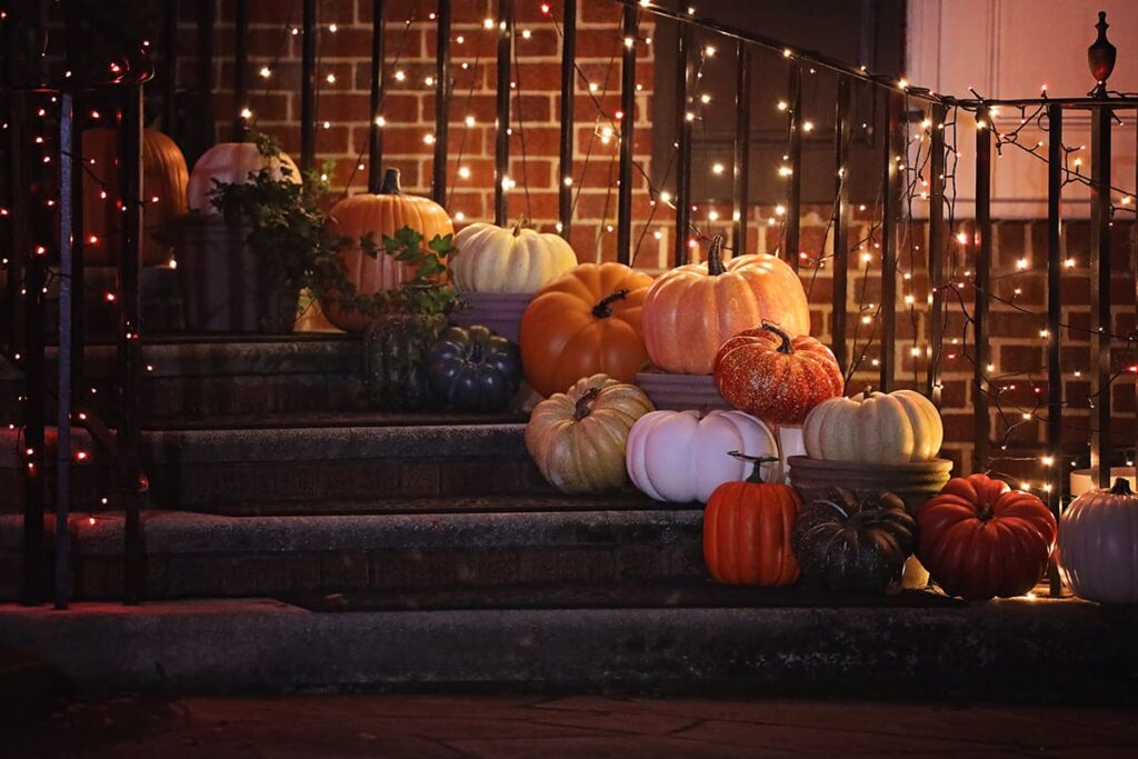 16 colorful pumpkins lit by twinkle lights on the stairs of a home in Ardsley Park with