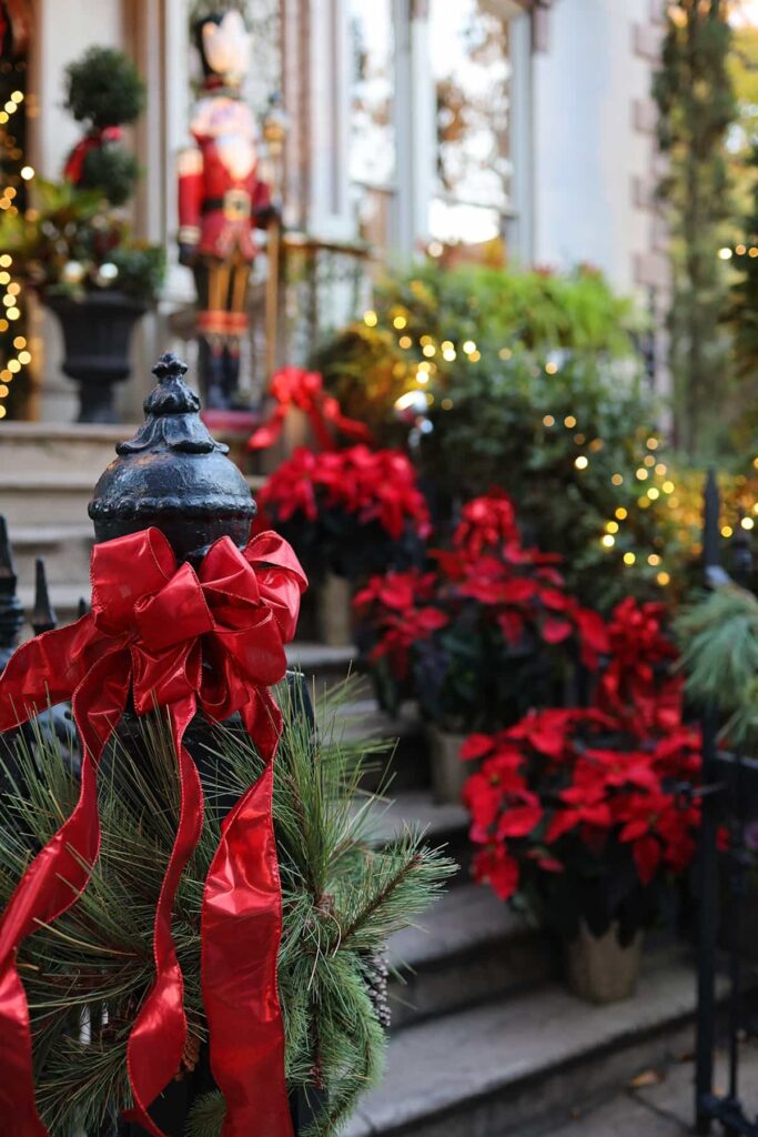Front entrance to the Hamilton-Turner Inn decorated for Christmas with red ribbons and poinsettias, oversized nutcrackers, and warm, white twinkle lights