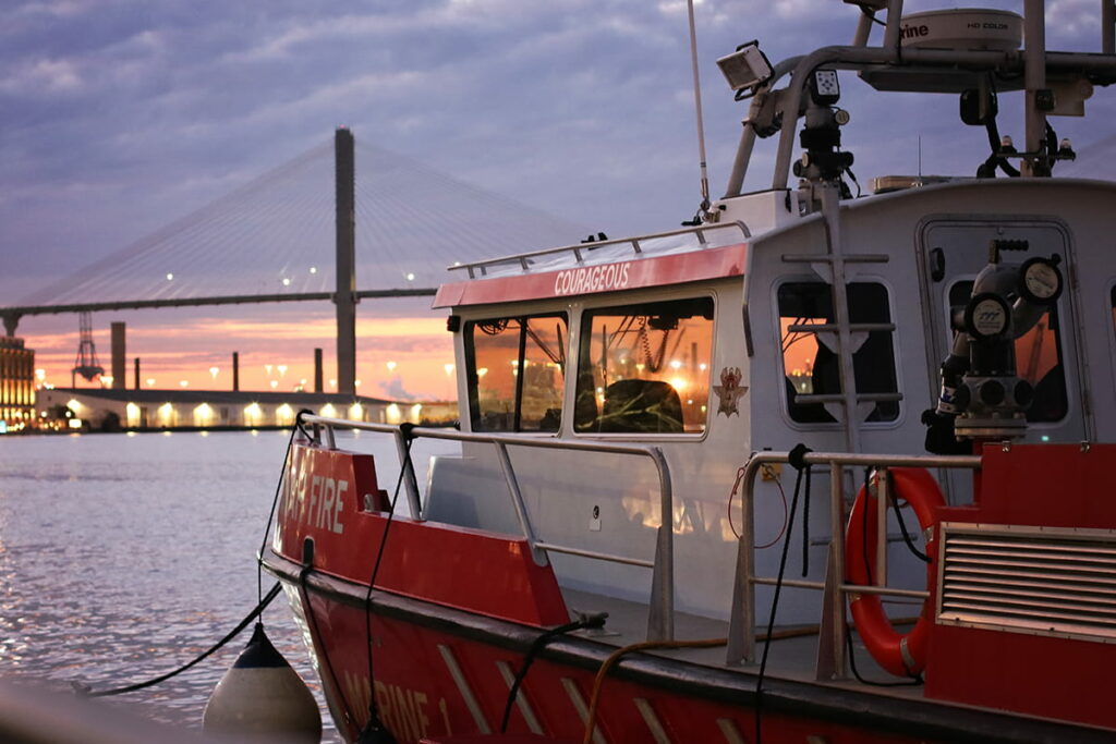 The Savannah Fire Department's "Courageous" rescue boat docked on River Street with a pretty purple sunset visible behind the Talmadge bridge in the background