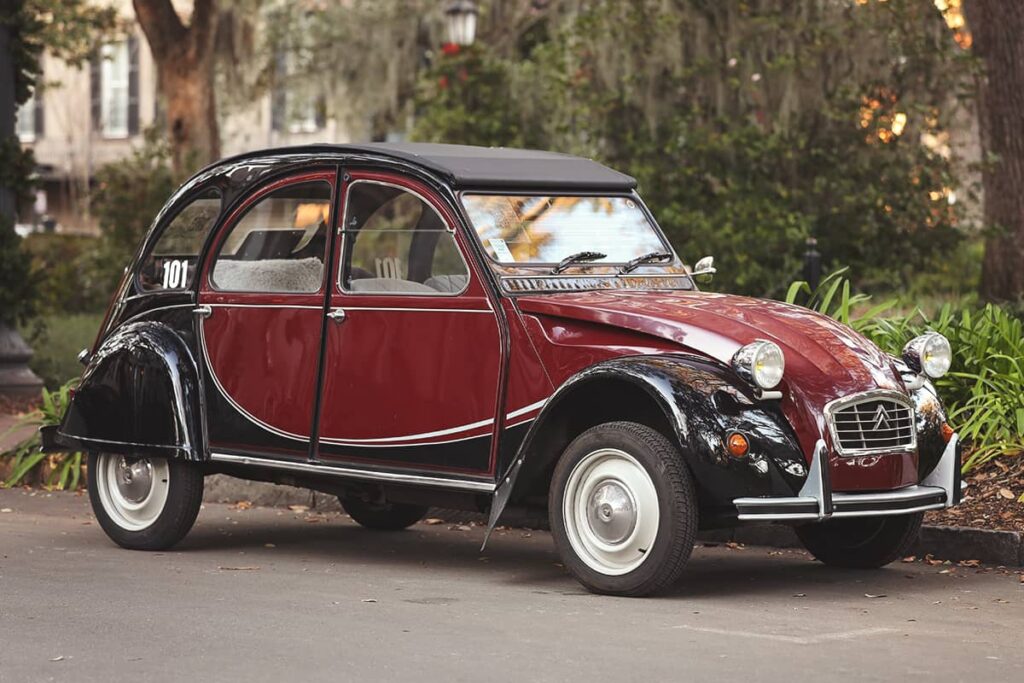 A garnet and black-colored Citroen from Savannah Vintage Tours parked in front of Monterey Square