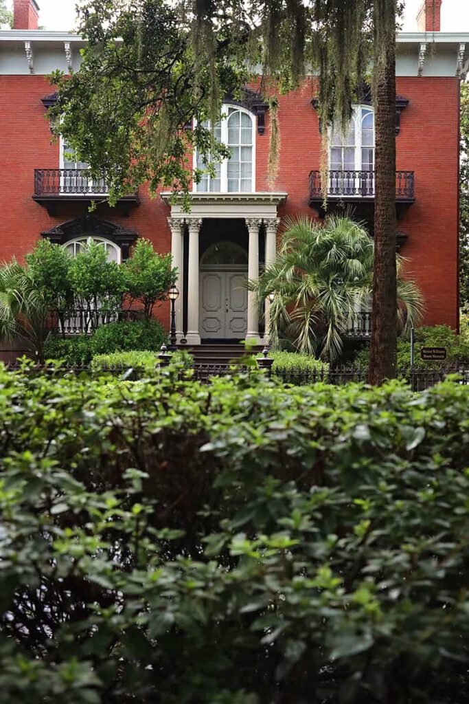 The entrance to the Mercer Williams House surrounded by lush summertime greenery with Spanish moss framing the top of the scene