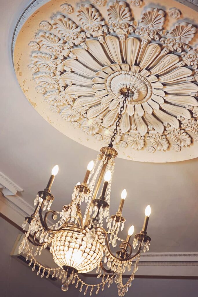 A beautiful brass and crystal chandelier hangs from a massive (probably 8-foot diameter) and intricate plaster off-white ceiling medallion at the Sorrel-Weed House