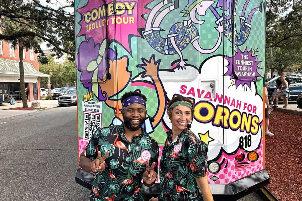 Danny and Dani flash peace signs while posing in front of the Savannah for Morons trolley